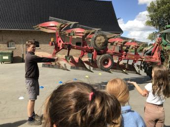 Landbouwer geeft uitleg aan kinderen bij machine
