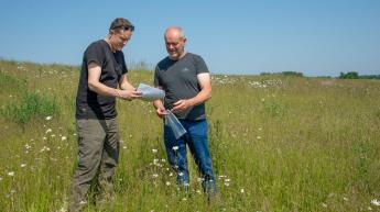 Landbouwer en bedrijfsplanner VLM op een veld