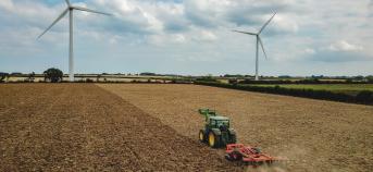 Tractor op het veld met windmolens op achtergrond